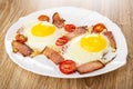 Fried eggs with gammon and cherry tomato in white dish on wooden table