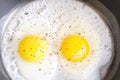 Fried eggs with spices on the black pan close-up. two eggs Royalty Free Stock Photo