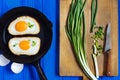 Fried eggs and spring onion on blue wooden background