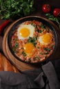 Fried eggs with stewed tomatoes , cast iron pan , on a wooden table,top view , rustic, vertical Royalty Free Stock Photo