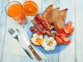 Fried eggs with toast, bacon and tomato on a plate