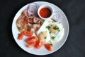 Fried eggs with tomatoes, red onion, bacon for breakfast on a white plate Royalty Free Stock Photo