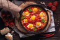 Fried eggs with tomatoes and vegetables. Shakshuka in a cast iron portioned pan on a wooden background top view Royalty Free Stock Photo