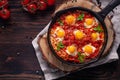 Fried eggs with tomatoes and vegetables. Shakshuka in a cast iron portioned pan on a wooden background top view Royalty Free Stock Photo