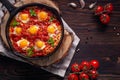 Fried eggs with tomatoes and vegetables. Shakshuka in a cast iron portioned pan on a wooden background top view Royalty Free Stock Photo