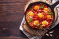 Fried eggs with tomatoes and vegetables. Shakshuka in a cast iron portioned pan on a wooden background top view Royalty Free Stock Photo