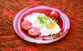 Fried eggs with vegetables on a red plate Royalty Free Stock Photo