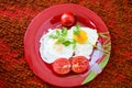 Fried eggs with vegetables on a red plate Royalty Free Stock Photo