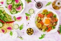 Fried eggs with vegetables - shakshuka and fresh salad cucumber, watermelon radish and arugula