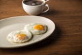 Fried Eggs on white plate and cup of black Coffee for Breakfast on wooden background Royalty Free Stock Photo