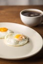 Fried Eggs on white plate and cup of black Coffee for Breakfast on wooden background Royalty Free Stock Photo