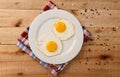 Fried eggs, on a white plate, on wooden background. Top Wiew