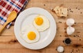 Fried eggs, on a white plate, on wooden background. Top Wiew