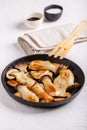 Fried eryngii mushrooms in cast-iron pan on white table. Grilled slices of king oyster mushrooms