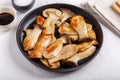 Fried eryngii mushrooms in cast-iron pan on white table. Grilled slices of king oyster mushrooms