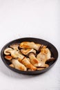 Fried eryngii mushrooms in cast-iron pan on white table. Grilled slices of king oyster mushrooms. Copy space