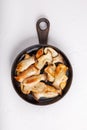 Fried eryngii mushrooms in cast-iron pan on white table. Grilled slices of king oyster mushrooms. Top view, copy space