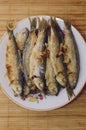 Fried fish Baltic herring lies on a plate on a bamboo napkin