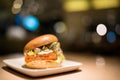 Fried fish burger with vegetable and cheese, under spotlight, blur bokeh dark background Royalty Free Stock Photo