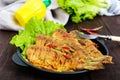 Fried fish carp sazan on a cast-iron frying pan with lettuce leaves