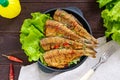 Fried fish carp sazan on a cast-iron frying pan with lettuce leaves