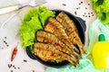 Fried fish carp sazan on a cast-iron frying pan with lettuce leaves on a light background.