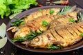 Fried fish carp sazan on a ceramic bowl with branches of rosemary