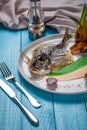 Fried fish dorado, decorated with cucumbers and onions. On a blue wooden background Royalty Free Stock Photo