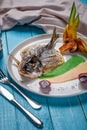 Fried fish dorado, decorated with cucumbers and onions. On a blue wooden background Royalty Free Stock Photo