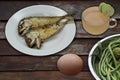 Fried fish, eggs, fresh vegetables and lemon juice on wooden background Royalty Free Stock Photo