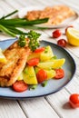 Fried fish fillets in batter, served with potato, tomato and scallion Royalty Free Stock Photo