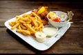 Fried fish, french fries, salad and sauces served on a white plate with newspaper decoration Royalty Free Stock Photo