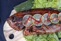Fried fish with fresh green salad and lemon of Bali, Indonesia, closeup. Delicious roasted sea fish with lemon on wooden plate in