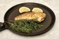 fried fish with lemon and herbs in a frying pan on the table Royalty Free Stock Photo