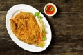 Fried fish on plate with vegetables on wood background