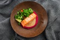 Fried fish salmon fillet with pink humus garnish. One piece of baked salmon grilled lime, tomatoes and salade on a brown plate .