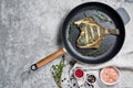 Fried flounder in a pan. Gray background, top view, space for text. Royalty Free Stock Photo