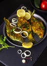 Fried Freshwater Fish with Lemon in a Plate on Black Slate Cutting Board