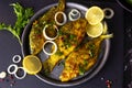 Fried Freshwater Fish with Lemon in a Plate on Black Slate Cutting Board