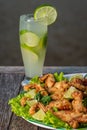 Fried frog legs with caipirinha cocktail on wooden table Royalty Free Stock Photo