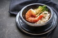 Fried giant prawn or shrimp with rice and pak choi in a black spotted ceramic bowl on a dark background, cooking in Asian style,