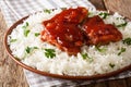 Fried glazed chicken thighs with sauce and rice close-up on a pl