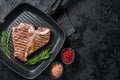 Fried on a grill skillet t bone porterhouse beef meat Steak. Black background. Top view. Copy space