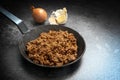 Fried ground beef with onion and garlic in a black pan on a dark