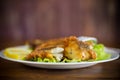 Fried hake fish in batter with lettuce and lemon in a plate