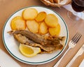 Fried hake served with boiled potatoes and lemon
