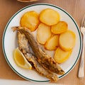 Fried hake served with boiled potatoes and lemon