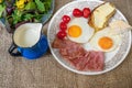 Fried ham and eggs, cherry tomato, bread with butter, cheese, blue pitcher with milk and salad, breakfast Royalty Free Stock Photo