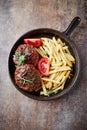 Fried hamburger steaks with tomatoes and french fries. Rustic background. Royalty Free Stock Photo