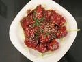 Fried juicy chicken pieces marinated with honey, soy sauce, spices, sprinkled with sesame seeds on a white plate. Asian recipe,